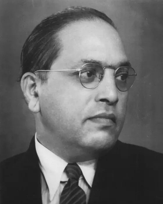 A black-and-white portrait of a man in round glasses, a suit and tie.