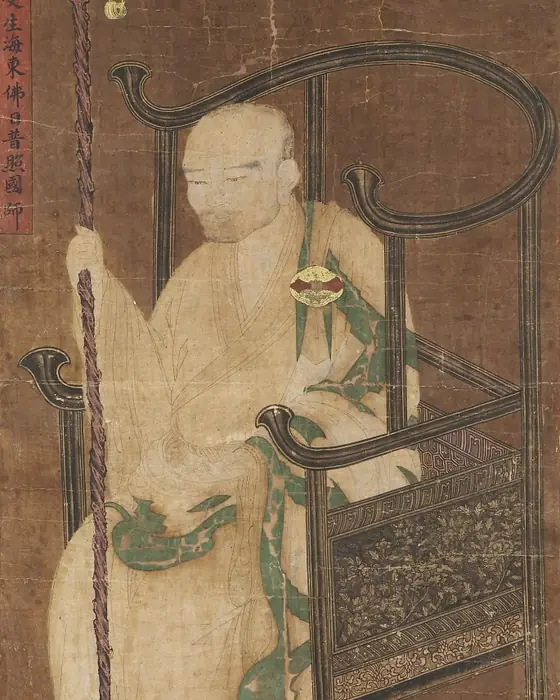 A painting of a seated monk in a green and red robe beside a carved chair.