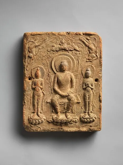 A small earthenware tile moulded with a seated Buddha flanked by two standing attendants.