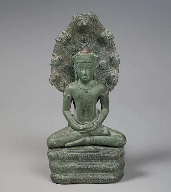 A bronze Buddha seated in meditation on the coils of a serpent, whose many heads rise behind him like a hood.